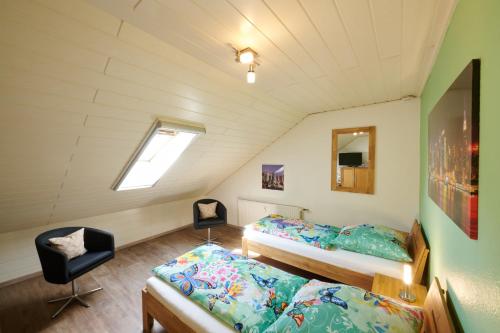 un dormitorio en el ático con 2 camas y una silla en Haus Gretchen Alpen en Xanten