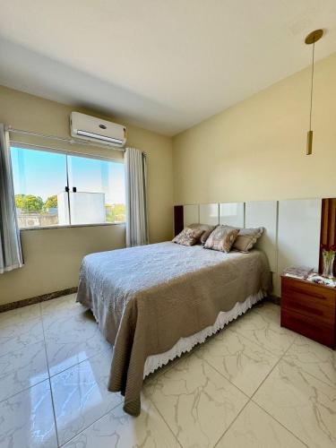 a bedroom with a large bed and a window at Apto Luxo completo 3 quartos em Guriri 300 mts da praia Wi-fi grátis in Guriri