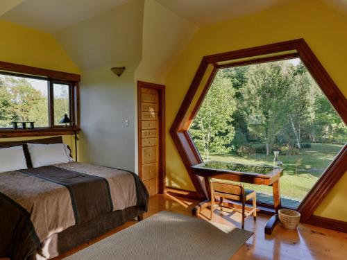 a bedroom with a bed and a large window at Sugar Hill Retreat #296692 in Lac-Brome