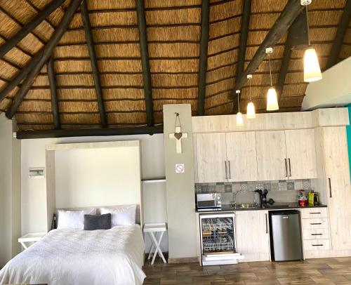 a bedroom with a large bed and a kitchen at LAKE-HOUSE CABIN in Witbank