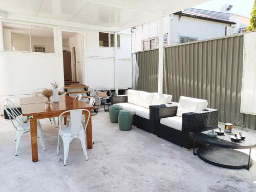 a patio with a couch and a table and chairs at Stunning Queen Room 1Min Walk to Station with 55 Inch TV in Sydney