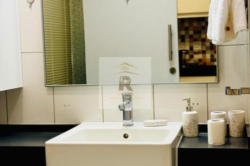 Palm View East Jumeira - Studio Apartment في دبي: حمام مع حوض أبيض ومرآة