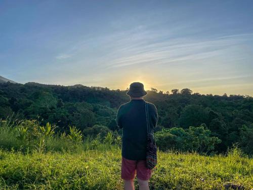 un hombre parado en un campo mirando la puesta de sol en Tetabatu Rice Terrace Homestay, en Tetebatu