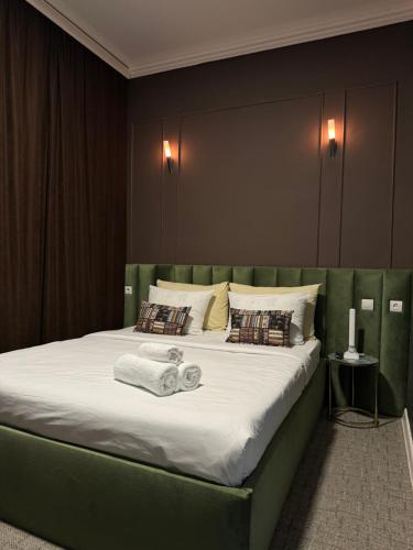 a bedroom with a large bed with a green headboard at Hotel NOMAD in Aktobe