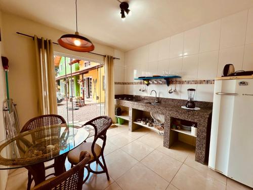 a kitchen with a table and chairs and a refrigerator at Vila Madu in Bombinhas