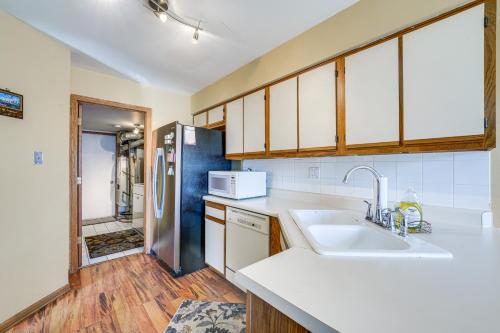 a kitchen with a sink and a refrigerator at Hanover Park Townhome with Grill 36 Mi to Chicago! in Hanover Park