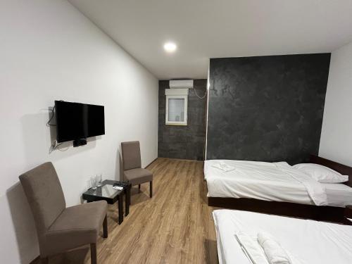 Schlafzimmer mit einem Bett, einem TV und einem Stuhl in der Unterkunft Apartmani Bosfor in Niška Banja