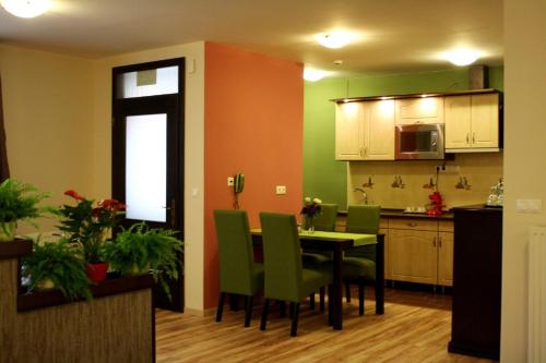 a kitchen with a dining table and green chairs at Ambrózia Étterem és Panzió in Kazincbarcika