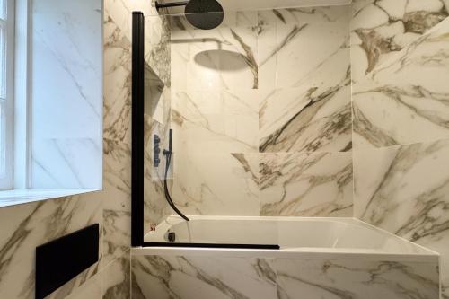 a bathroom with a tub and a shower with marble walls at Be London - Farringdon Apartments in London