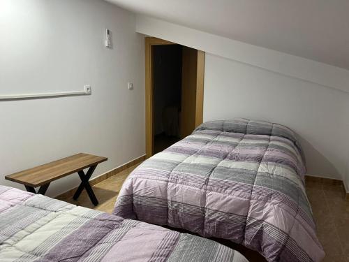1 dormitorio con 2 camas y mesa de madera en CASA RURAL SAN GREGORIO, en Las Eras