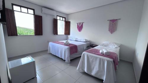 a room with two beds and two windows at Pousada Estrelar in Lençóis