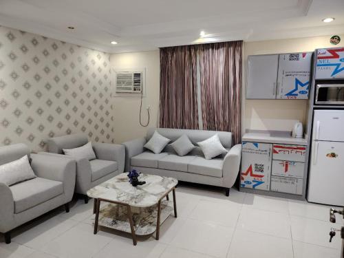 a living room with couches and a table and a kitchen at العالية للشقق المفروشه الشهري in Jeddah