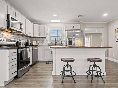 a kitchen with white cabinets and two bar stools at Beautiful 3 Bedroom Home in Lake Charles