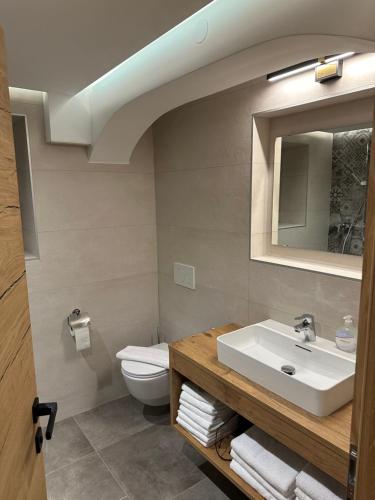 łazienka z umywalką, toaletą i lustrem w obiekcie Ferienwohnung Krallinger w mieście Wenns