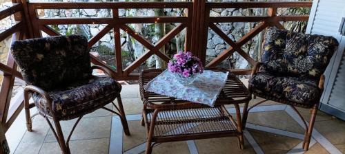 two chairs and a table with flowers on a porch at Η θέα Τhe View in Lílaia
