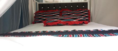 Una cama con almohadas rojas y negras. en Hotel Judith Laroo en Gulu