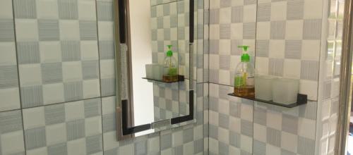 Baño con espejo y 2 botellas en la pared en Hotel Judith Laroo en Gulu