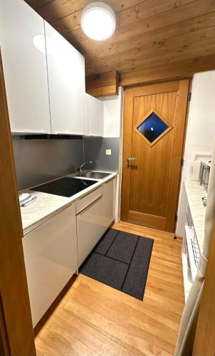 a kitchen with white cabinets and a wooden door at Landhaus Solaris in Leutasch