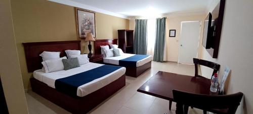 a hotel room with two beds and a desk at Hotel Confort Plaza in Culiacán