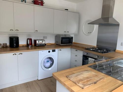 uma cozinha com armários brancos e uma máquina de lavar roupa em Cottage nr BikeParkWales/Brecon Beacons/PenYFan em Merthyr Tydfil