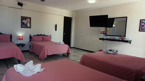 a hotel room with two beds and a flat screen tv at Hotel Murallas 231 in Campeche
