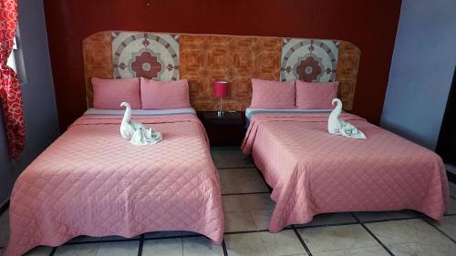 two beds in a room with two swans on them at Hotel Murallas 231 in Campeche