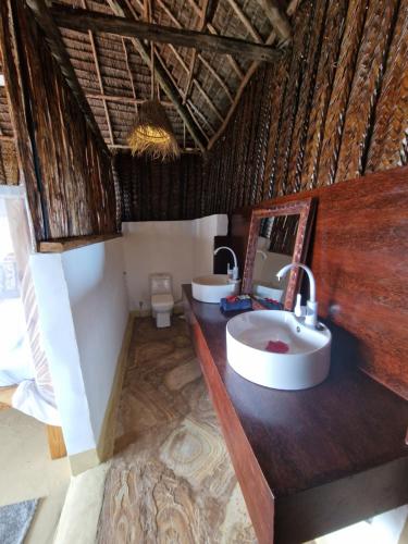 a bathroom with two sinks and a toilet at Mtende Beach Bungalow océan view in Mtende