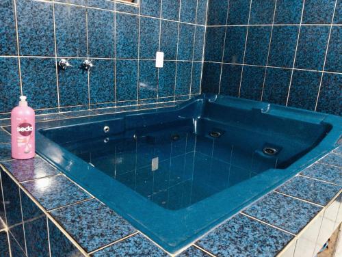 uma banheira azul numa casa de banho em azulejo com uma garrafa rosa em Hostel família Campineira em Campinas