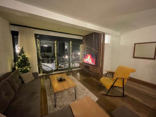 a living room with a fireplace and a christmas tree at Bonvillas Brezovicë riverside apartments in Brezovica