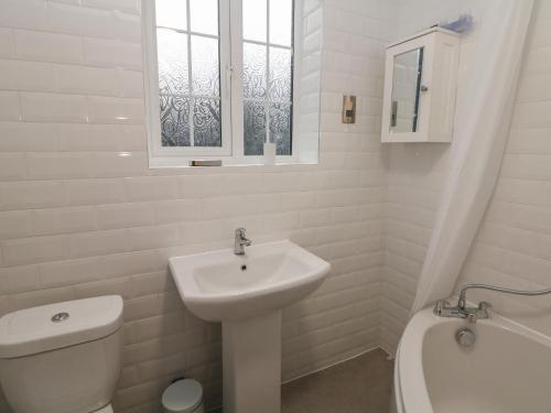 Baño blanco con lavabo y aseo en Quarry Cottage, en Buxton