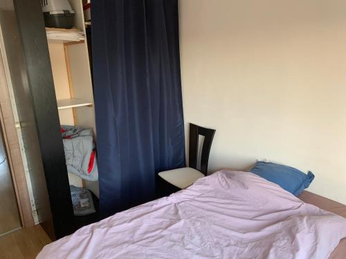 - une chambre avec un lit et un rideau bleu dans l'établissement Chambre dans appartement, à Bagneux