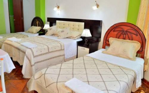 2 camas en una habitación con paredes verdes en Hostal Mansion Dorada, en Tacna
