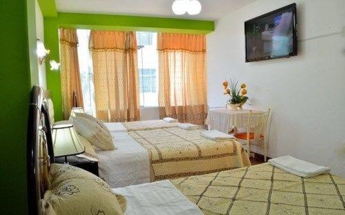 a bedroom with two beds and a flat screen tv at Hostal Mansion Dorada in Tacna