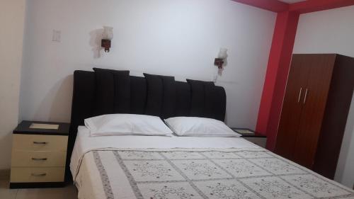 a bedroom with a large bed with a black headboard at Hostal Mansion Dorada in Tacna