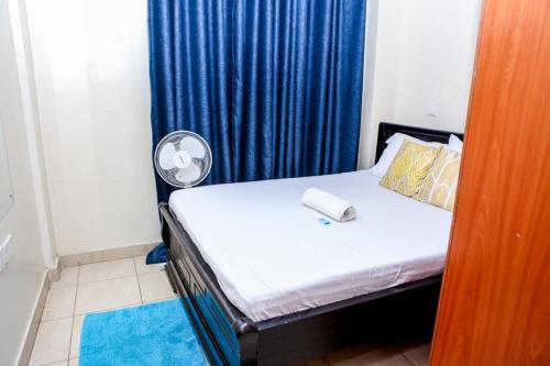a bedroom with a bed with a fan and a blue curtain at Belch Apartment in Kisumu