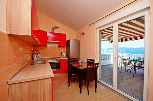 a kitchen with red cabinets and a table and a balcony at Apartment Luxury Cream in Kaštela