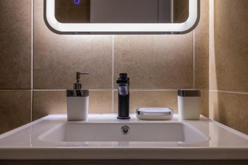 lavabo con dispensador de jabón y espejo en Luxury Central Apartment 2, en Xanthi