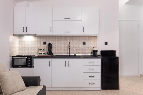 a kitchen with white cabinets and a black refrigerator at Luxury Central Apartment 2 in Xanthi