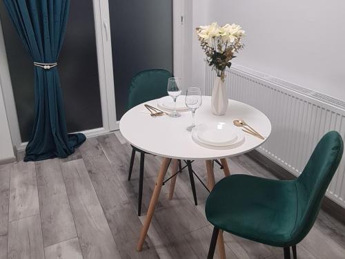 a white table with a vase of flowers and wine glasses at Pallady Studio 85 in Bucharest