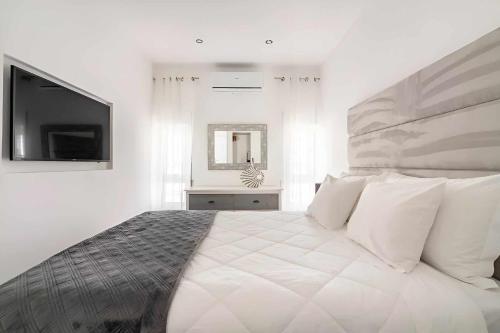 a white bedroom with a large bed and a flat screen tv at Timeless Beach I Apartment in Armação de Pêra