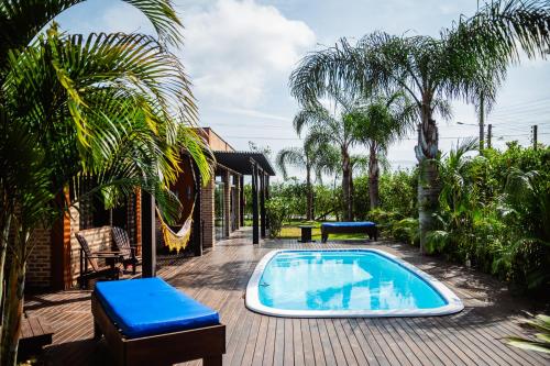 un patio con piscina y palmeras en Ibiraquera Life, en Praia do Rosa