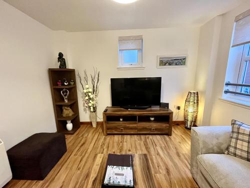 uma sala de estar com uma televisão de ecrã plano em La Scala Inverness City Apartment em Inverness