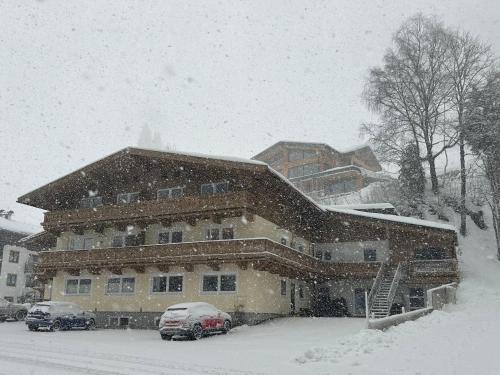 a snow covered house with cars parked in front of it at Haus Dienten Top 11 in Dienten am Hochkönig