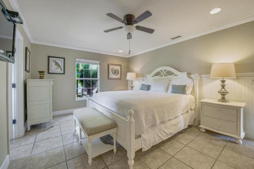 una camera con letto bianco e ventilatore a soffitto di Calypso Cottage a Holmes Beach