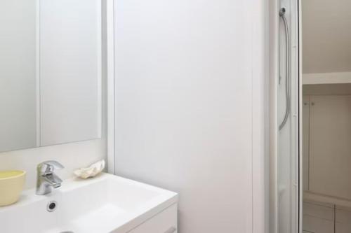 La salle de bains blanche est pourvue d'un lavabo et d'une douche. dans l'établissement VILLA FLOIRAC ANGLET CENTRE, à Anglet