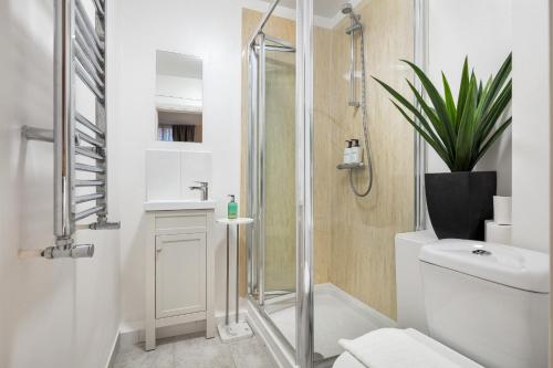 uma casa de banho com um chuveiro, um WC e uma planta em Elegant Kensington Apartment with patio em Londres