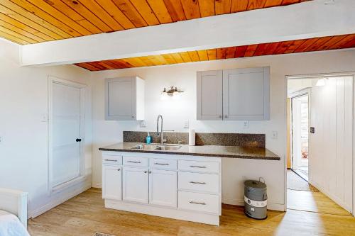 uma cozinha com armários brancos e um tecto de madeira em Casa KD em Running Springs