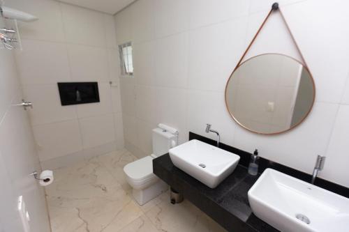 a white bathroom with a sink and a mirror at Wafeh Fleming Suítes Pampulha in Belo Horizonte