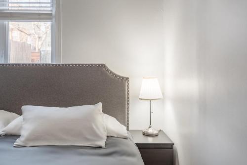 Cama con almohadas blancas y mesa con lámpara en AAA Location Condo & FREE Parking, en Montreal