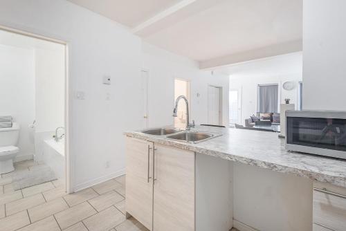 a white kitchen with a sink and a microwave at AAA Location Condo & FREE Parking in Montreal